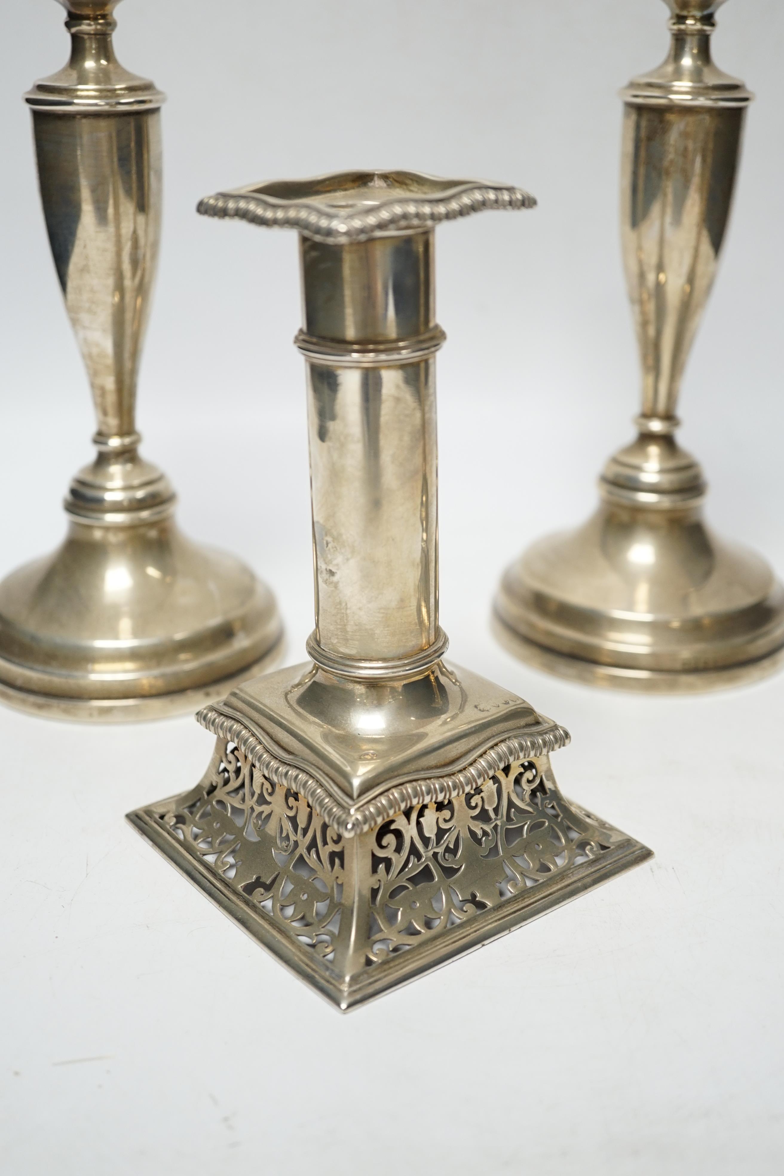 A pair of Victorian silver candlesticks, on pierced swept bases, William Leuchars, London, 1886, 15.2cm, weighted and a later taller pair of silver candlesticks.